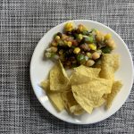 Recipe and corn tortilla chips on a white plate placed on a checkered tablecloth