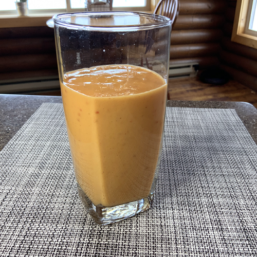 orange smoothie in clear glass on checkered placemat