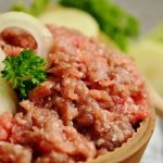 Ground meat in small bowl, fresh onion rings on top