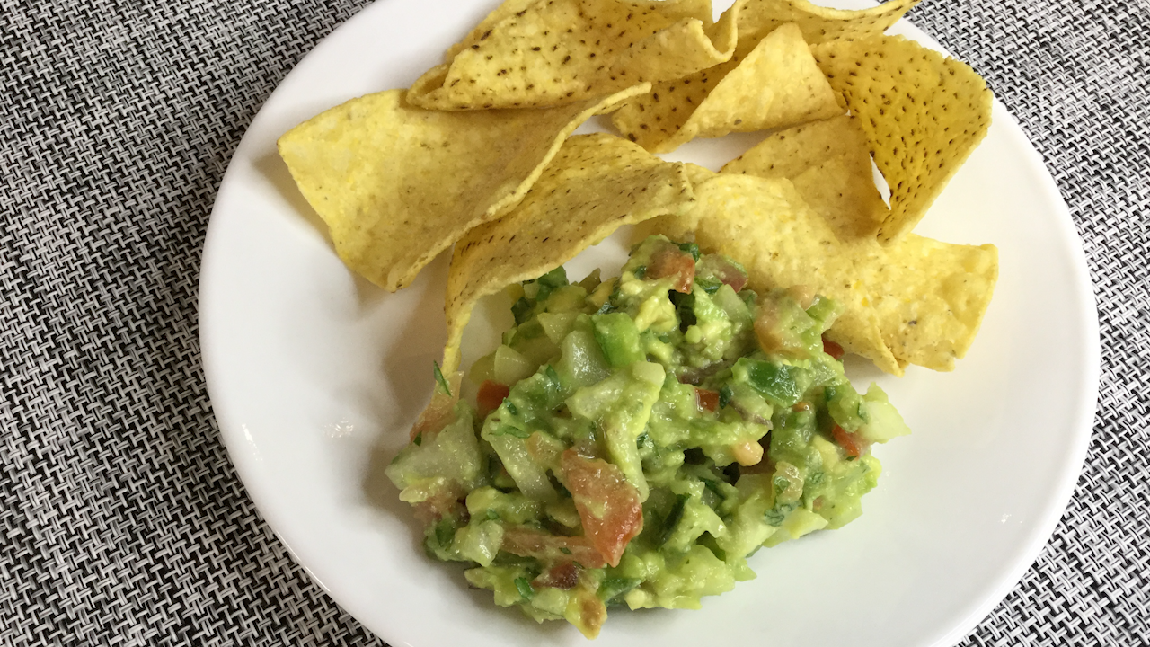 serving of guacamole with corn tortilla chips on white plate
