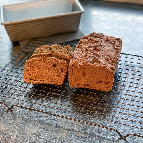 Loaf of bread on cooling rack with stacked slices