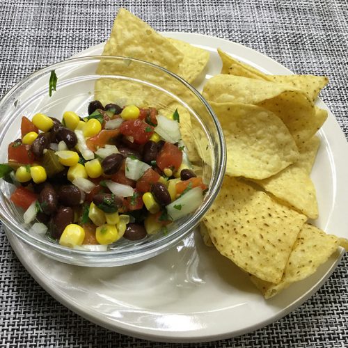 salsa in small bowl with tortilla chips on plate