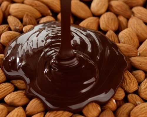 chocolate being poured onto raw almonds