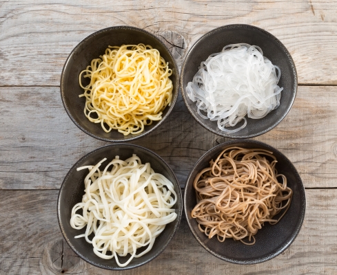 Four types of Asian noodles in black bowls