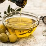 olive oil in glass bowl with olives on the side