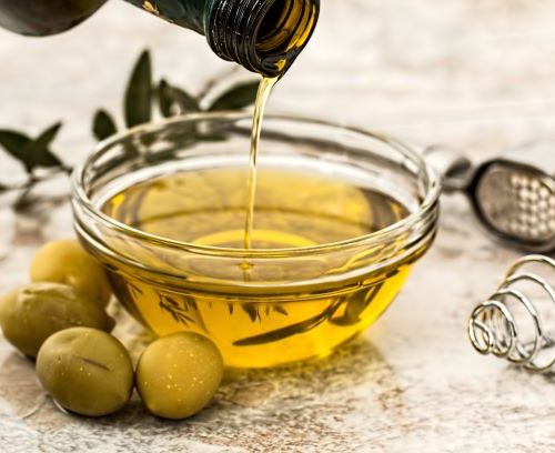 olive oil in glass bowl with olives on the side