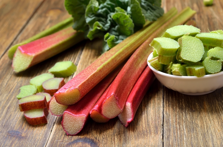 Rhubarb stalks without their leaves, some sliced in a bowl