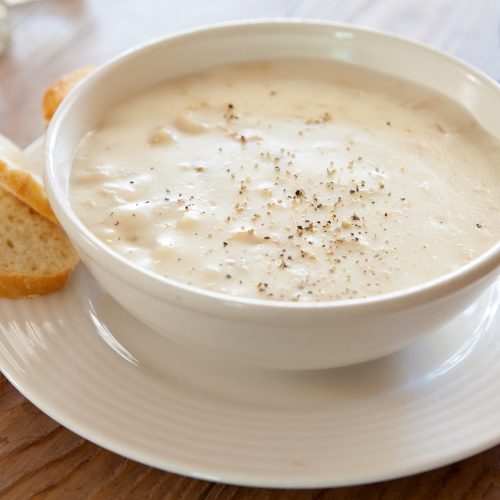 bowl of clam chowder with bread on the side