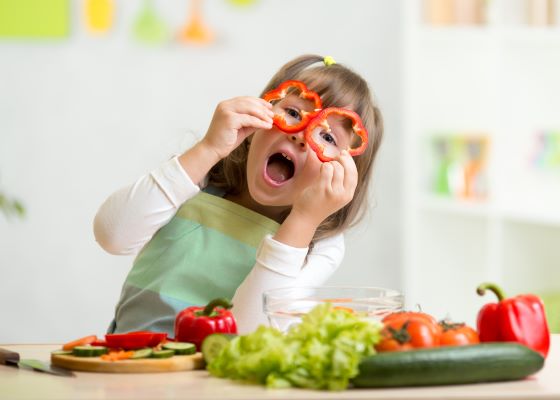 Child holding red pepper slices up to face like glasses