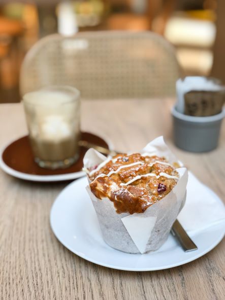 muffin on small plate with saucer and drink in background