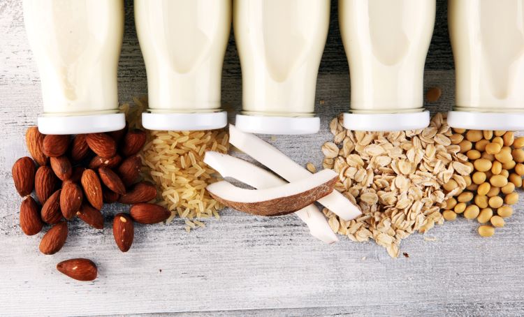 Almonds, Rice, Coconut, Oats, Soybeans on wood next to bottles of milk