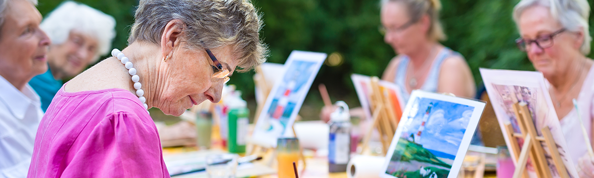 Photograph of three older adults engaged in an art activity, with an older woman in a pink shirt in the foreground focused on her project. This image supports the UW Extension A.G.E. blog article titled 'Healthy Sleep Habits.