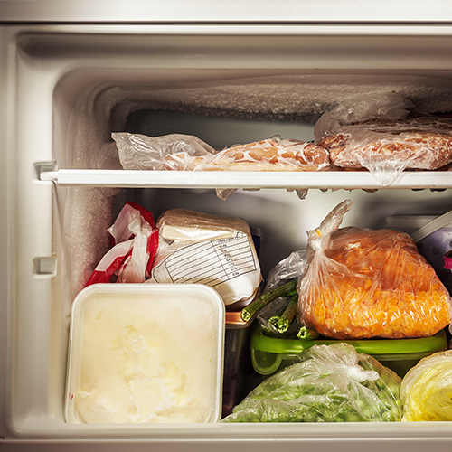 Home freezer filled with packaged meat and frozen vegetables stored for long-term preservation.