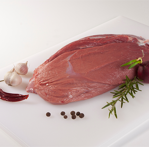 Raw cut of wild game meat on a white cutting board with garlic, chili pepper, rosemary, black peppercorns, and a red onion.