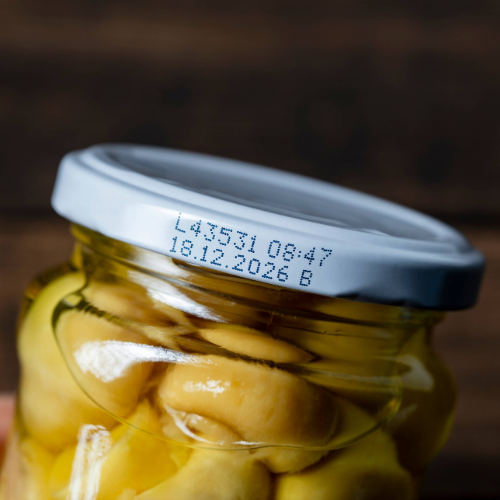 Close-up of a jar lid with a printed expiration date on the top of the container.