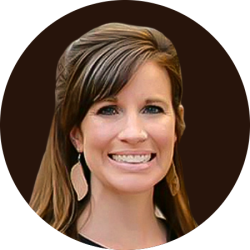 Portrait of Kali McKrackin Goodenough, smiling and wearing a black turtleneck, standing in front of a neutral brown background. Kali is a featured author on the UW Extension A.G.E. blog
